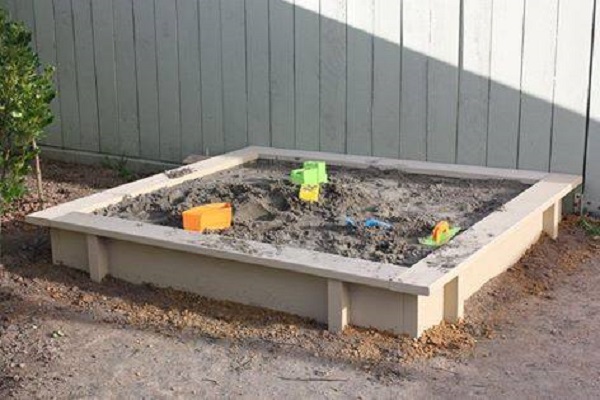 kids sandpit with wooden edges, filled with sand.